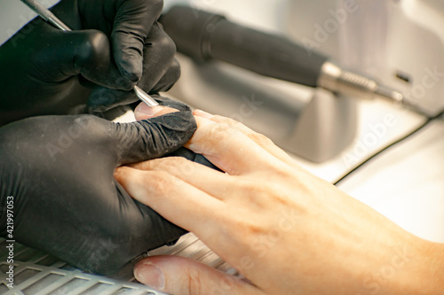 Finger cuticle treatment with manicure tools in a professional salon.