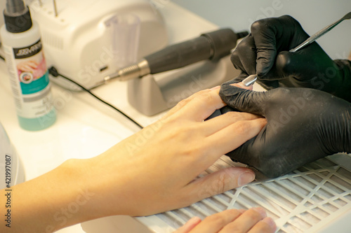 Finger cuticle treatment with manicure tools in a professional salon. © Ilia Petukhov