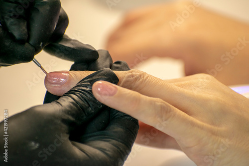 Nail treatment in a beauty salon. Application of the final coat of varnish.