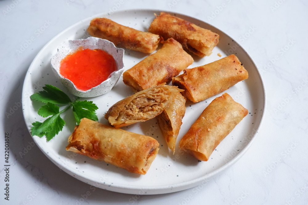 a plate of fried spring rolls served with sauce