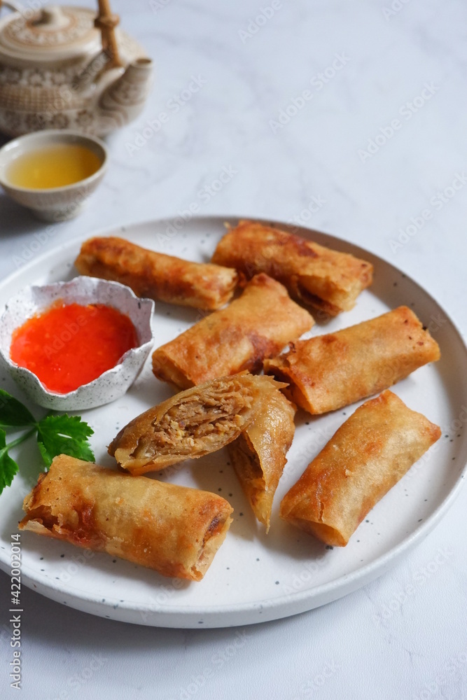 a plate of fried spring rolls served with sauce