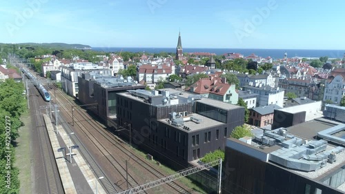 A long-distance train departing from the railway station against the backdrop of a seaside town. The sea is visible in the distance. The shot was captured on a beautiful sunny summer day.