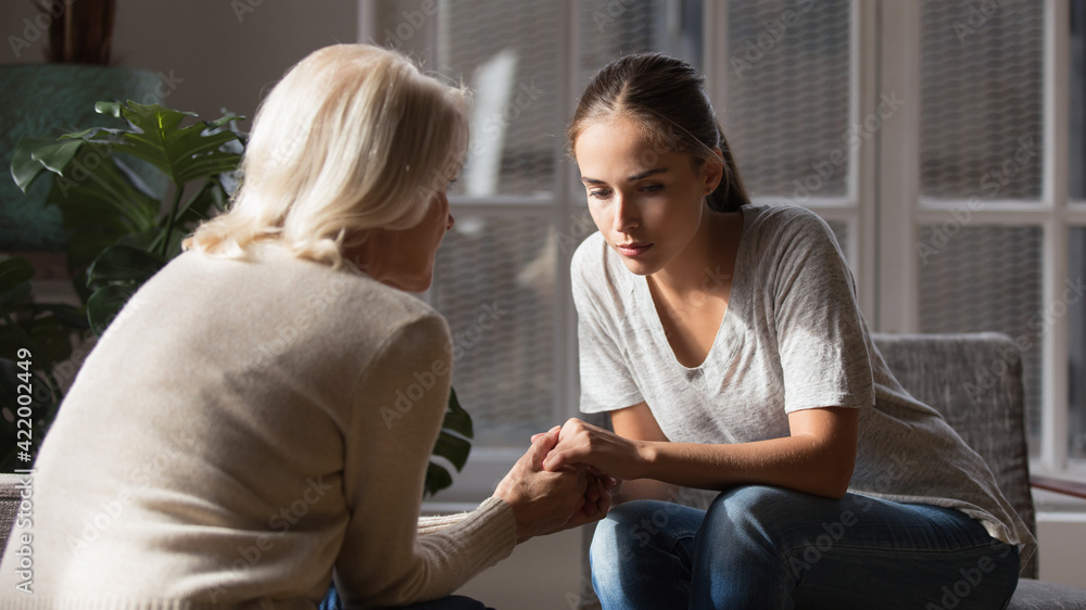 Supportive older Caucasian mom hold hands comfort caress talk with millennial female child feeling unhappy sad. Loving senior mother show support and care to upset depressed adult grownup daughter. Supportive older Caucasian mom hold hands comfort caress talk with millennial female child feeling unhappy sad. Loving senior mother show support and care to upset depressed adult grownup daughter.