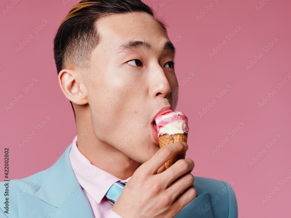 The guy of Korean appearance Clear ice cream on a pink background and looks to the side cropped view The guy of Korean appearance Clear ice cream on a pink background and looks to the side cropped view