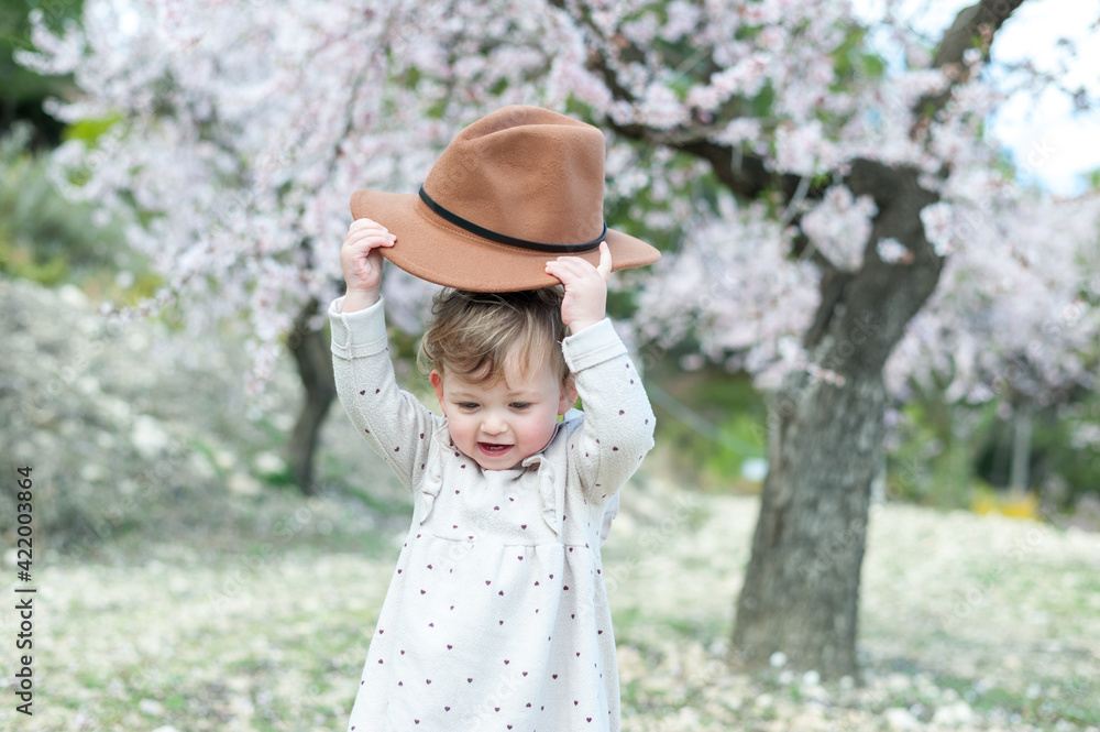 Little girl playing with hat at the park. Spring concept Little girl playing with hat at the park. Spring concept