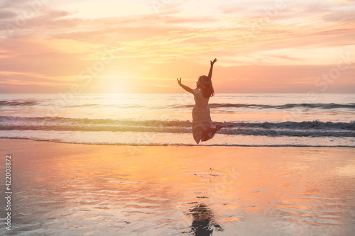 Young woman jumping on the beach at beautiful sunset, Summer vacation concept