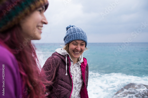 two girls laugh on the beach while walking