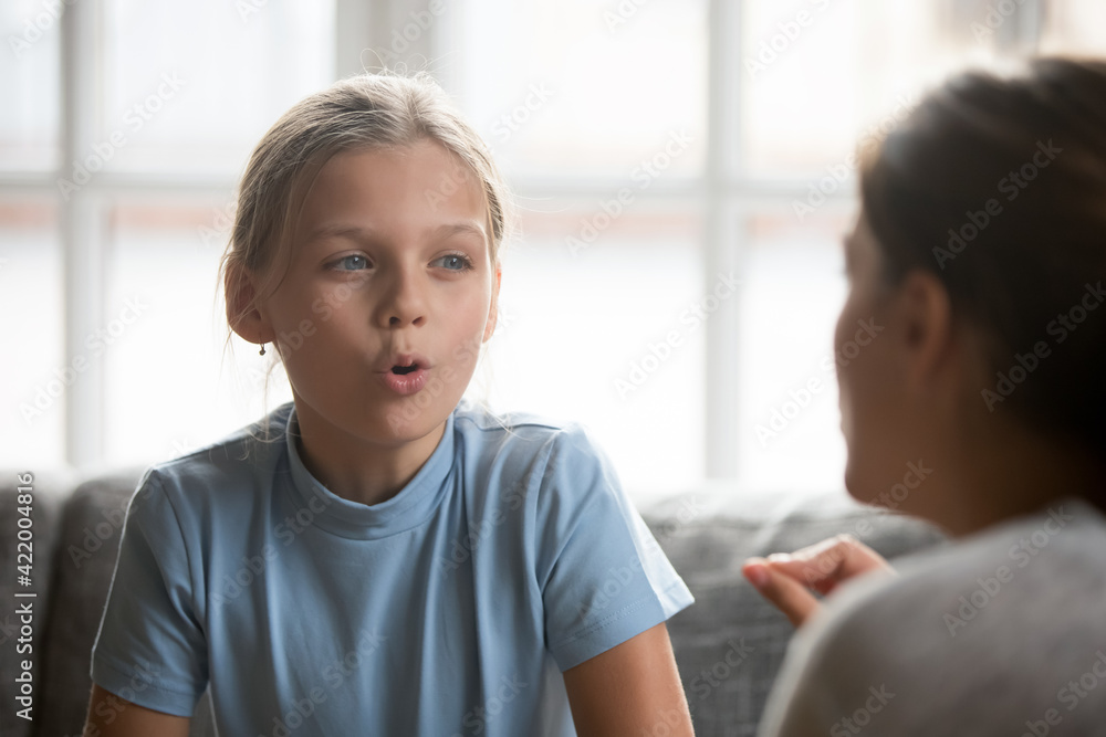 Small Caucasian teen girl child do articulation exercises with caring mother or teacher at home. Little kid pronounce sounds speak talk with tutor or coach, engaged in voice pronunciation together. Small Caucasian teen girl child do articulation exercises with caring mother or teacher at home. Little kid pronounce sounds speak talk with tutor or coach, engaged in voice pronunciation together.