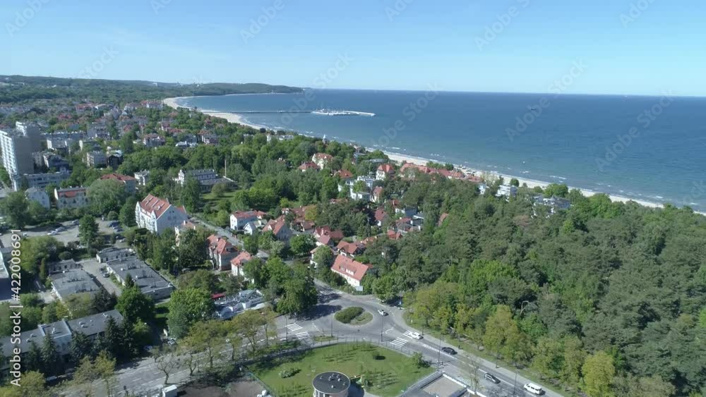 Seaside city landscape from the bird's eye view. In the foreground there are urban buildings with lots of green trees. In the distance, you can see the Baltic Sea and the famous Sopot Pier. Seaside city landscape from the bird's eye view. In the foreground there are urban buildings with lots of green trees. In the distance, you can see the Baltic Sea and the famous Sopot Pier.