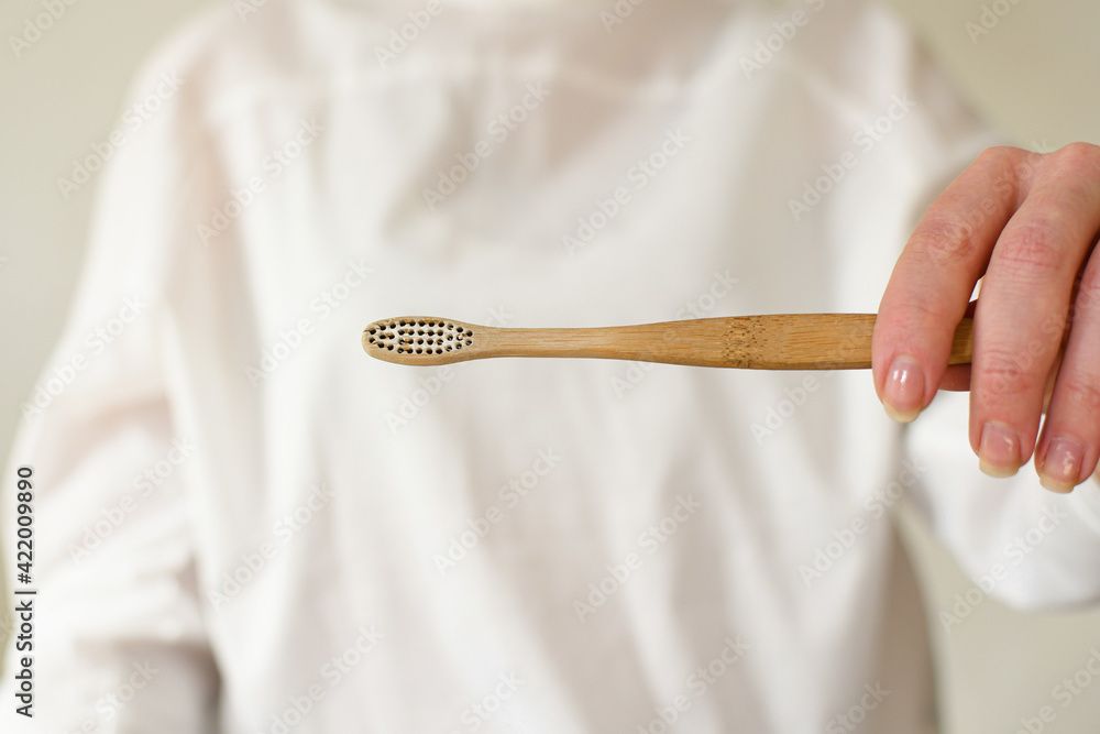 A woman shows how to properly dispose of a bamboo toothbrush, tears off the shield with pliers