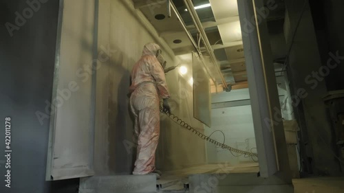 Wallpaper Mural Worker in protective suit sprays powder paint from gun on metal products Torontodigital.ca