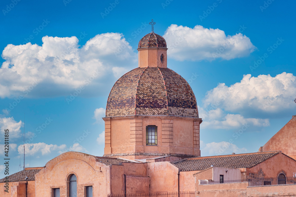 Ancient church dome with baroque cross. Sacred building with typical seventeenth century architecture. Bell tower decorated with scale tiles. Cathedral with double octagonal dome of baroque art.