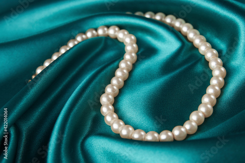 Pearl necklace on green background, close-up