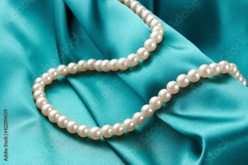 Pearl necklace on green background, close-up