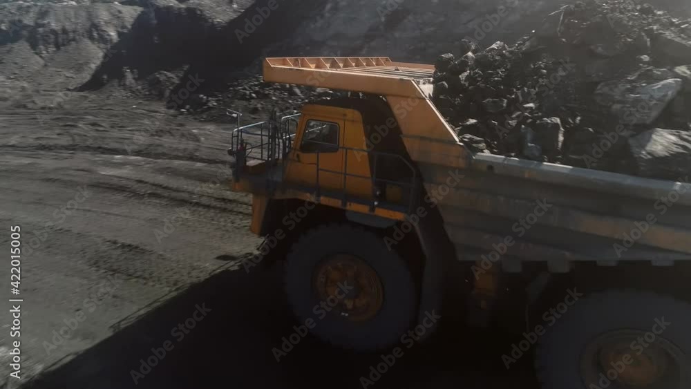 Large quarry dump truck. Loading rock in dumper. Loading coal into truck. Mining car machinery to transport coal. Open pit mine quarrying extractive industry stripping work. Big Yellow Mining Trucks Large quarry dump truck. Loading rock in dumper. Loading coal into truck. Mining car machinery to transport coal. Open pit mine quarrying extractive industry stripping work. Big Yellow Mining Trucks