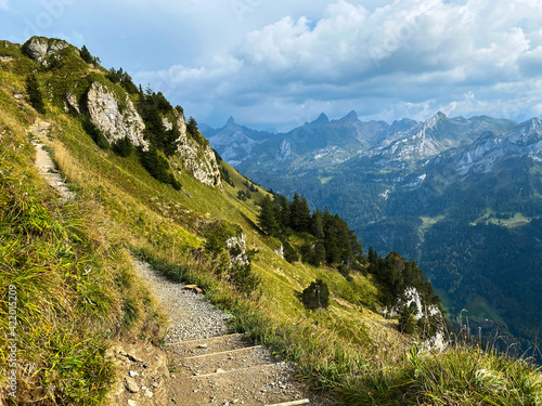 Hiking path with stairs in Swiss Alps. Breathtaking view of the peaks of the mountains in sunny summer day.