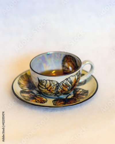 decorated tea mug with saucer on a white background