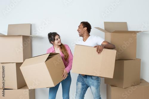 Multi ethnic couple in a new apartment with boxes having fun during the move.