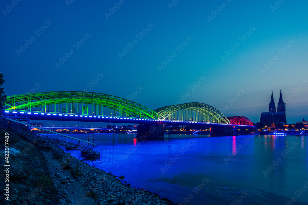 Panoramic view of Cologne Cathedral with Hohenzollern Bridge at the blue hour, Germany.