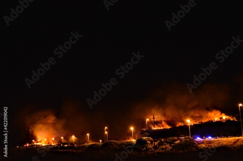 forest fire at night next to highway and police blocking traffic