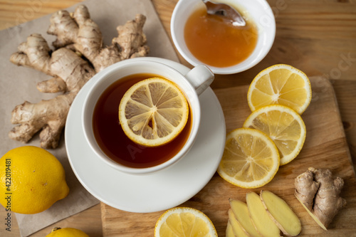 Cup of ginger tea with honey and lemon on wooden table