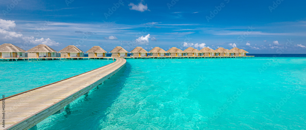 Ocean lagoon bay view, blue sky and clouds with wooden jetty and over water bungalows, villas, endless horizon. Meditation relaxation tropical background, sea ocean water. Skyscape seascape background