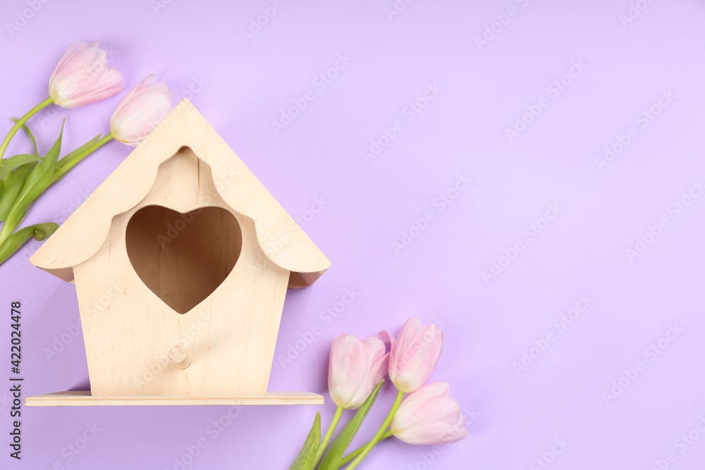 Beautiful bird house and pink tulips on violet background, flat lay. Space for text