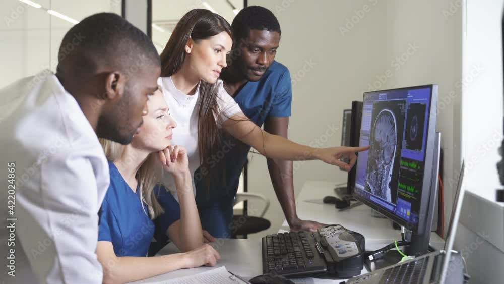 Team of radiologists looking at patient CT scan image at display discussing treatment of patient in x-ray room. Medical planing treatment concept. Team of radiologists looking at patient CT scan image at display discussing treatment of patient in x-ray room. Medical planing treatment concept.