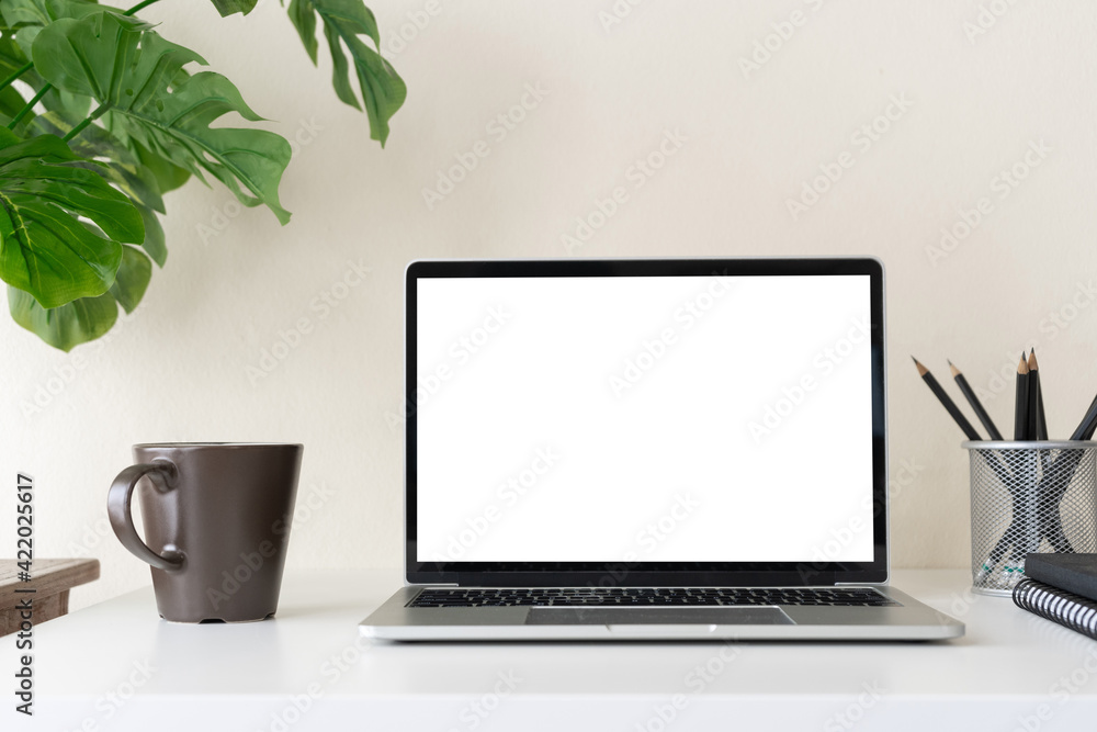 Laptop computer with blank screen for mockup on modern contemporary workspace desk with coffee cup and office supplies. Home office workplace. Laptop computer with blank screen for mockup on modern contemporary workspace desk with coffee cup and office supplies. Home office workplace.
