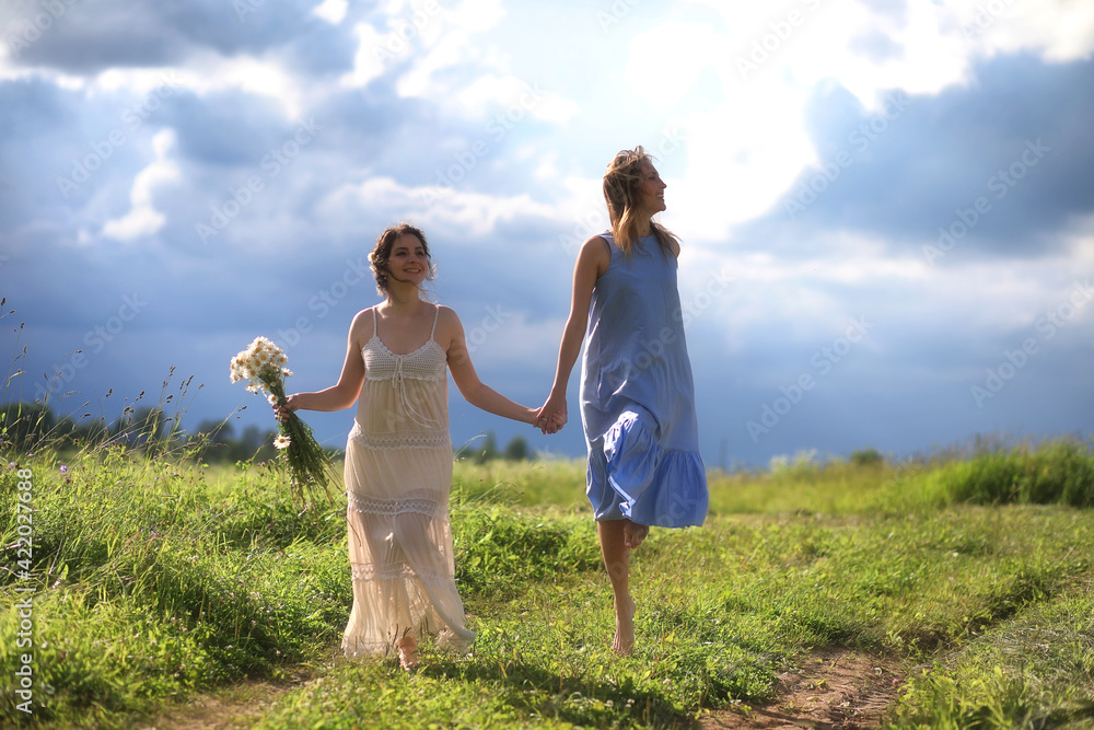 Fototapeta premium Young girls are walking in the field