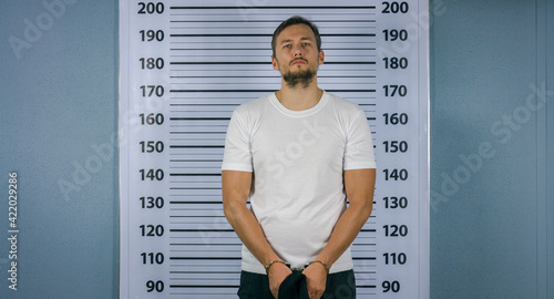 Картината върху платно Arrested a man in handcuffs standing near a white board with a scale