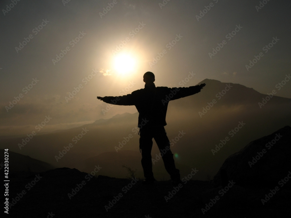 The silhouette of a man raised his hands against the background of the sunset The silhouette of a man raised his hands against the background of the sunset