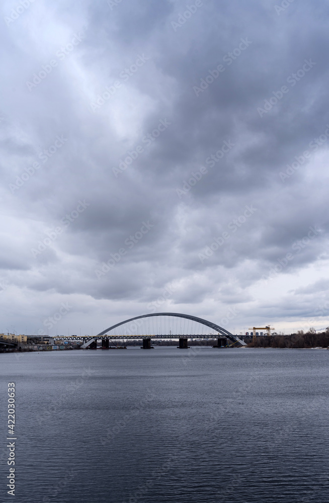 Fototapeta premium Podilsko-Voskresensky bridge under the dark skies in Kyiv