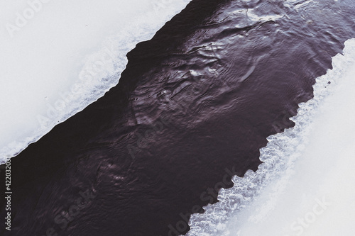 Lenaelva River at Toten, Norway, seen through an opening in the ice at winter. photo