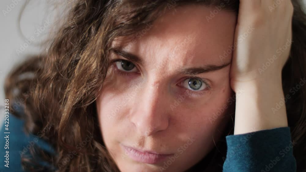 Close up portrait of beautiful annoyed young woman looking at the camera. Gorgeous Caucasian girl with pretty face and blue eyes and intense angry stare resting on hand. Slow-motion, 4K. Close up portrait of beautiful annoyed young woman looking at the camera. Gorgeous Caucasian girl with pretty face and blue eyes and intense angry stare resting on hand. Slow-motion, 4K.