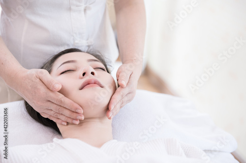 Young Asian woman getting spa massage treatment at beauty spa salon. Face massage, Relaxing massage, Spa skin and body care