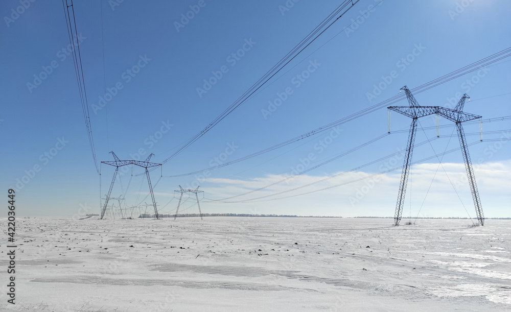 winter weather conditions. snowy field. Clear blue sky, power lines in the field, rural scene. winter weather conditions. snowy field. Clear blue sky, power lines in the field, rural scene.