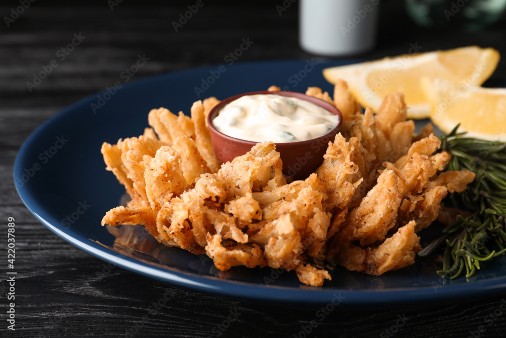 Fried blooming onion with dipping sauce served on dark wooden table, closeup Fried blooming onion with dipping sauce served on dark wooden table, closeup