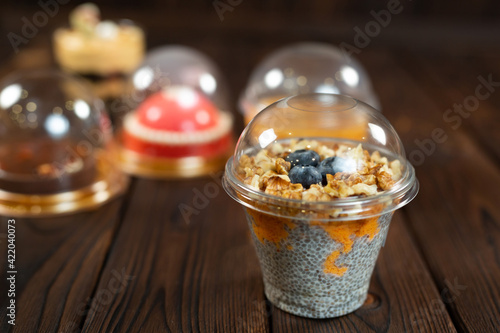 Variety of desserts in cups, including chia pudding on a brown wooden background.