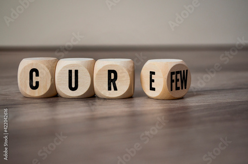 Cubes, dice or blocks with cure and curfew on wooden background © Stockwerk-Fotodesign