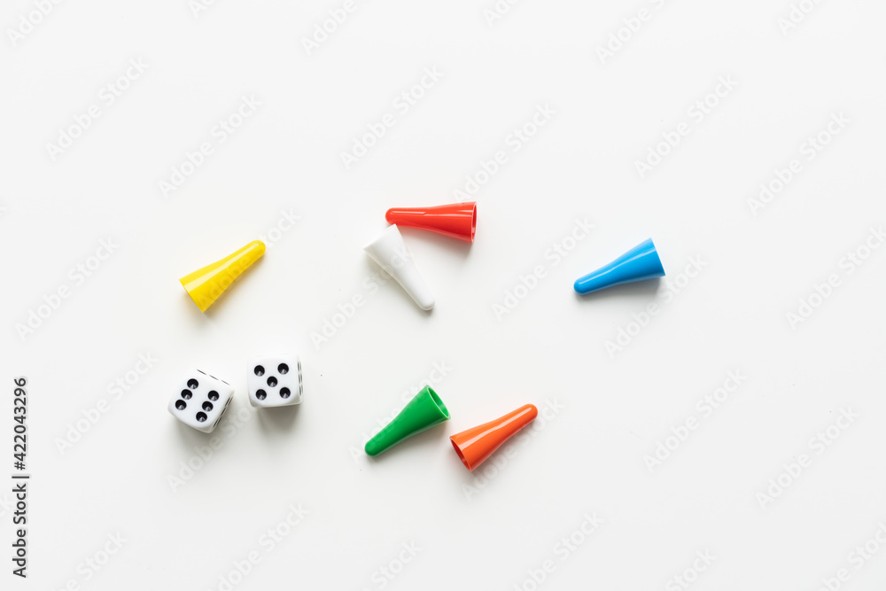 Multi-colored playing chips and dice cubes are grouped together on a white background: the concept of Board games, entertainment, background, games at home for the whole family Multi-colored playing chips and dice cubes are grouped together on a white background: the concept of Board games, entertainment, background, games at home for the whole family
