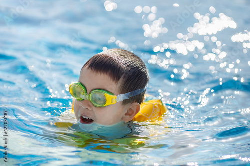 portrait of little boy swims in the pool