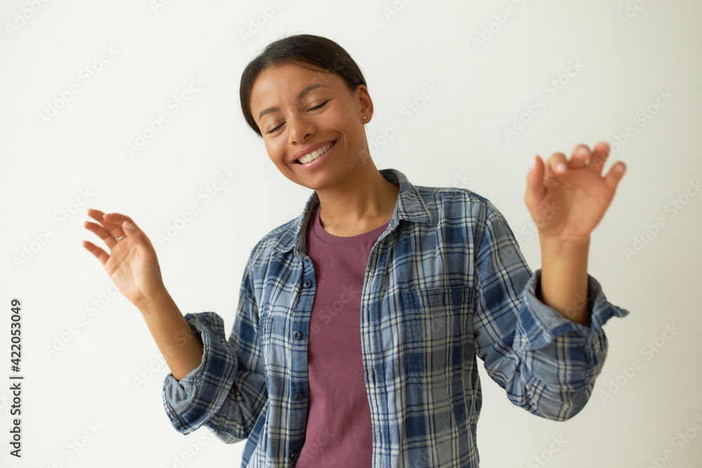 Horizontal shot of charming pleased young dark skinned Hispanic female closing eyes with enjoyment gesturing and smiling broadly, having happy cheerful look, posing isolated in casual clothes Horizontal shot of charming pleased young dark skinned Hispanic female closing eyes with enjoyment gesturing and smiling broadly, having happy cheerful look, posing isolated in casual clothes