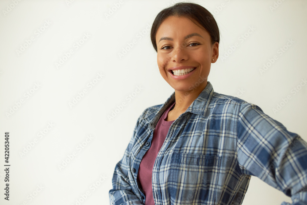 Attractive optimistic young mixed race female having confident smile posing isolated against blank wall background with copy space for your text, advertising content or promotional information Attractive optimistic young mixed race female having confident smile posing isolated against blank wall background with copy space for your text, advertising content or promotional information