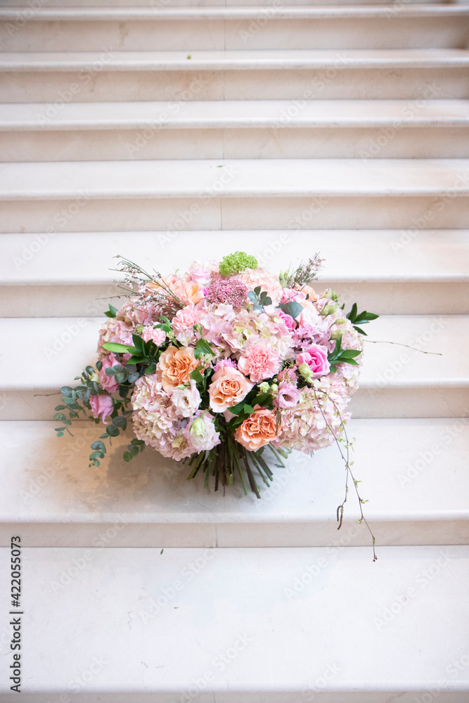 Fototapeta premium a large bouquet of pink, white flowers, on a light staircase. Bouquet, composition for a holiday, celebration. Flower trade, private business, floristic decoration