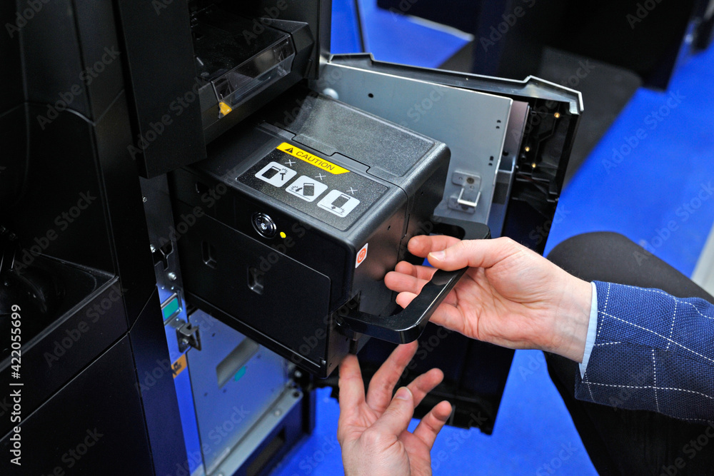 Man hands taking the cash cassette from the cash recycler Man hands taking the cash cassette from the cash recycler