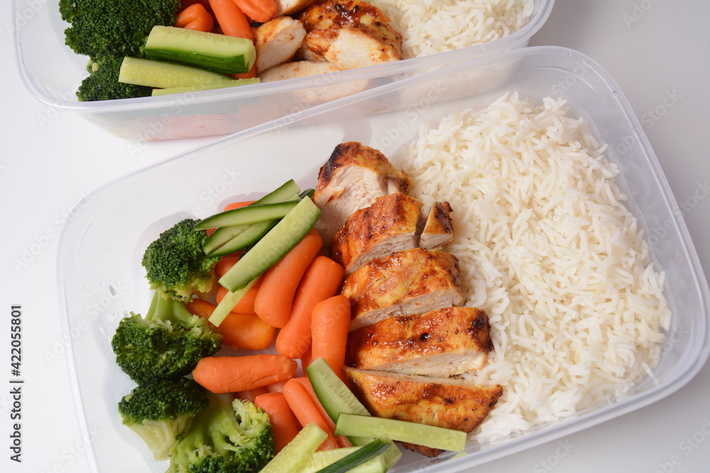 Healthy balanced lunch boxes. Grilled chicken, carrots, cucumbers, broccoli, and white rice. Lunch boxes with food ready to go for work or school. Office food lunch concept Healthy balanced lunch boxes. Grilled chicken, carrots, cucumbers, broccoli, and white rice. Lunch boxes with food ready to go for work or school. Office food lunch concept