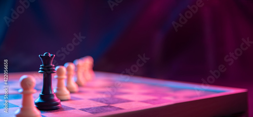 Chess pieces on a chessboard on a dark background shot in neon pink-blue colors. The figure of a chess .Close up.