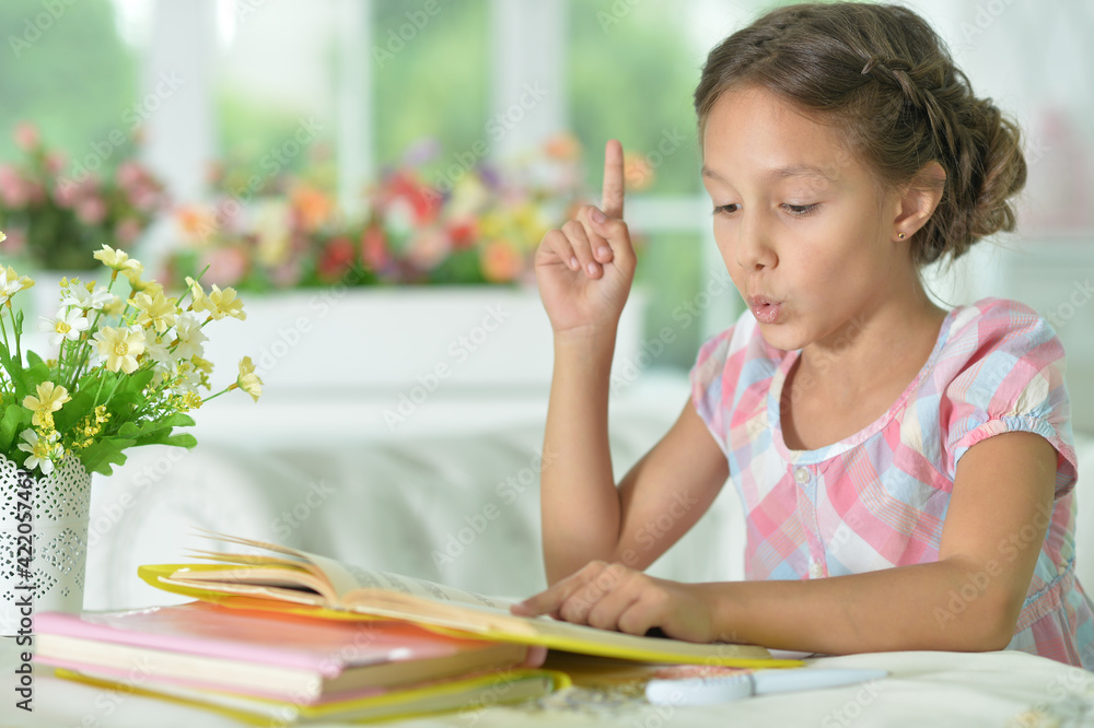 little cute girl reading book at the table at home little cute girl reading book at the table at home