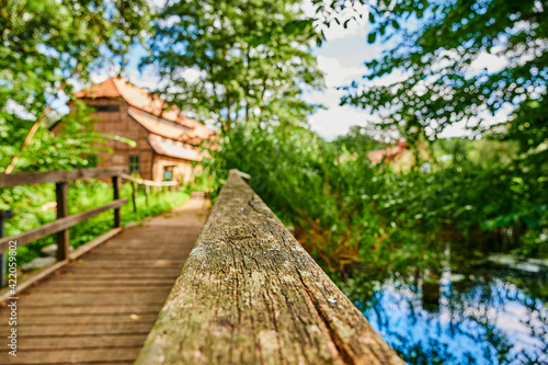 Wooden bridge over a creek as part of an old small weir near a historic watermill. The view goes along the wooden handrail.